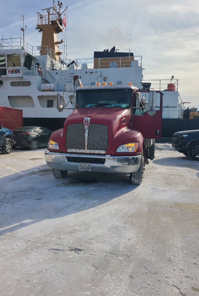 Front view of large red semi. Truck is parked in front of a boat